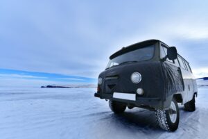 Pneu hiver ou été ? Une camionnette noire est sur une route enneigée