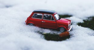 Chaîne neige. Une petite voiture rouge posée sur la neige.
