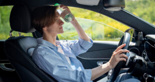 Femme au volant utilisant une bouteille d’eau pour se rafraîchir.